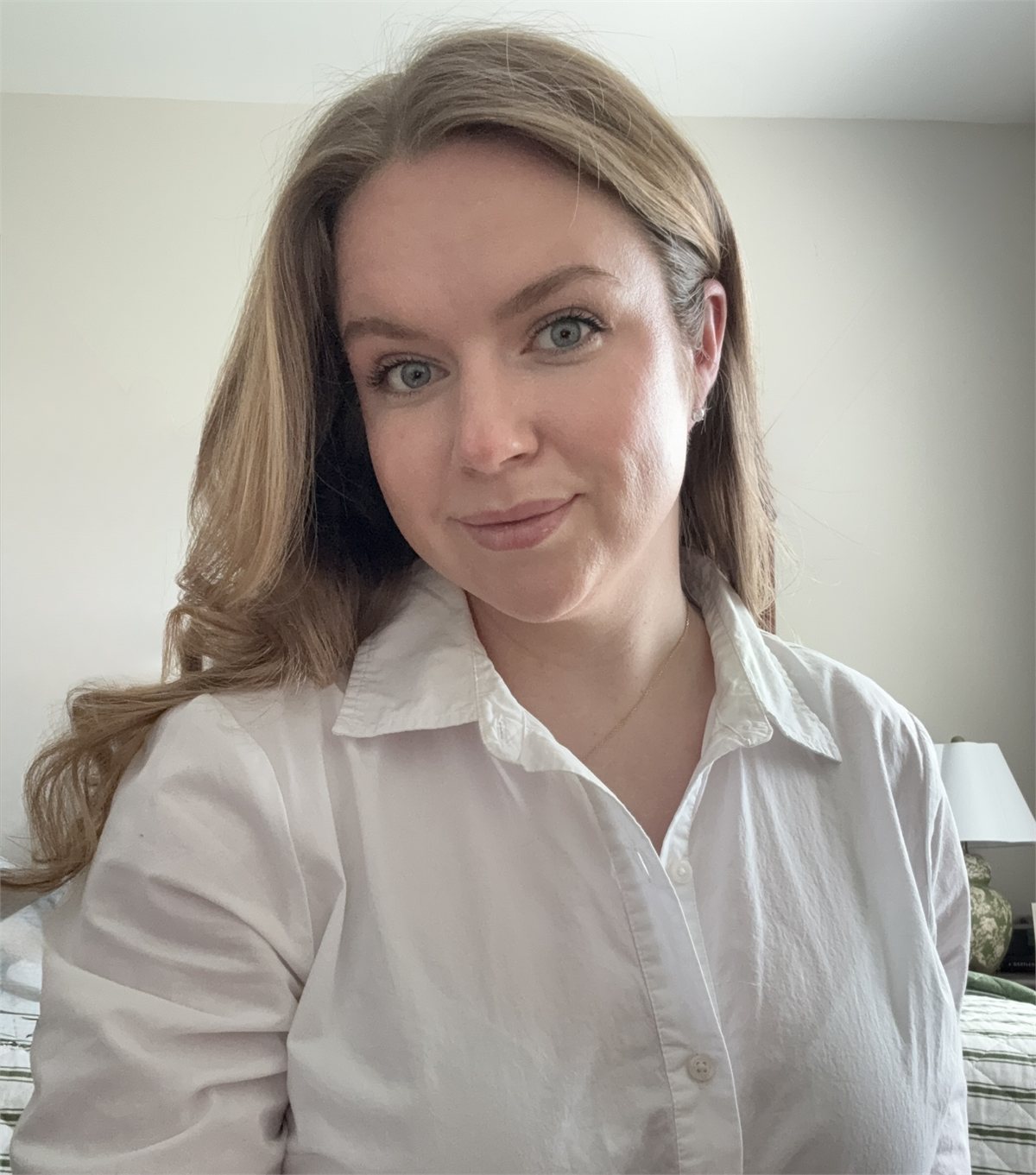 Masha, a therapist with long light-brown hair, smiling warmly in a white shirt